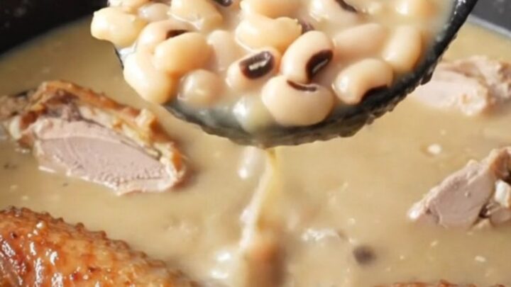 A close-up of a bowl of creamy swamp soup filled with smoked turkey wings, black-eyed peas, and turnip greens.