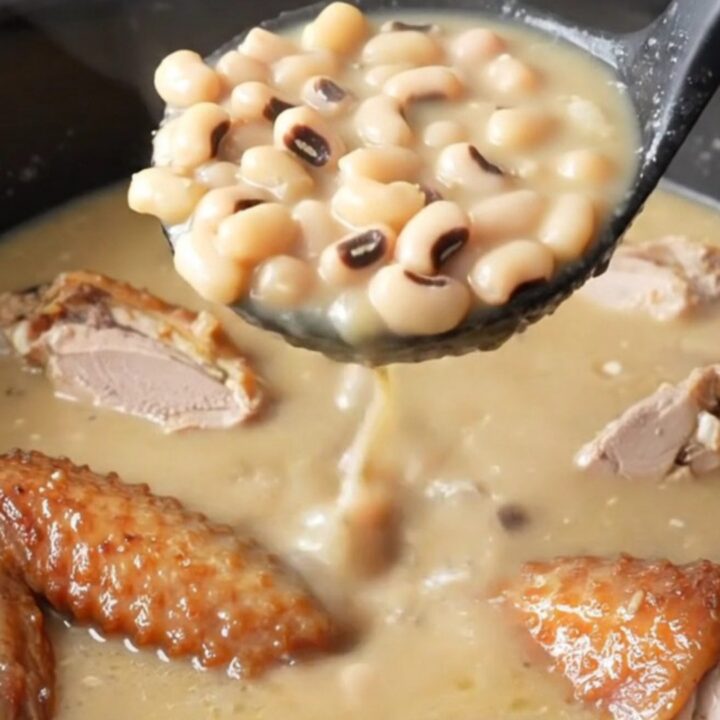 A close-up of a bowl of creamy swamp soup filled with smoked turkey wings, black-eyed peas, and turnip greens.