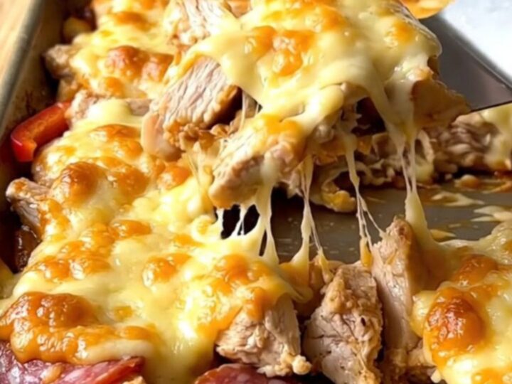 A sheet pan filled with golden melted provolone over roasted chicken, salami, and colorful peppers.