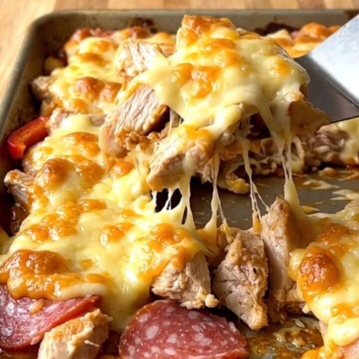 A sheet pan filled with golden melted provolone over roasted chicken, salami, and colorful peppers.