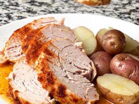 A slow cooker filled with a whole turkey breast and baby red potatoes, seasoned with smoky red paprika.