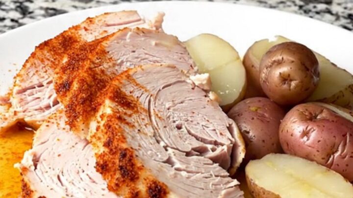 A slow cooker filled with a whole turkey breast and baby red potatoes, seasoned with smoky red paprika.