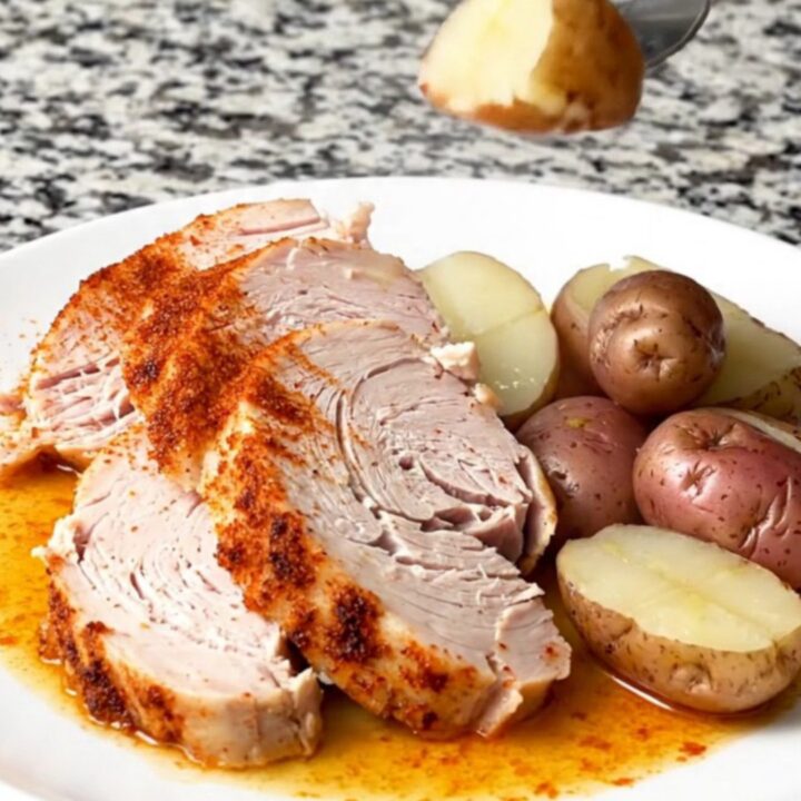 A slow cooker filled with a whole turkey breast and baby red potatoes, seasoned with smoky red paprika.