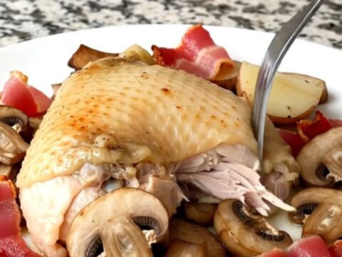 Slow cooker chicken thighs with bacon, mushrooms, and potatoes in a black stoneware insert.