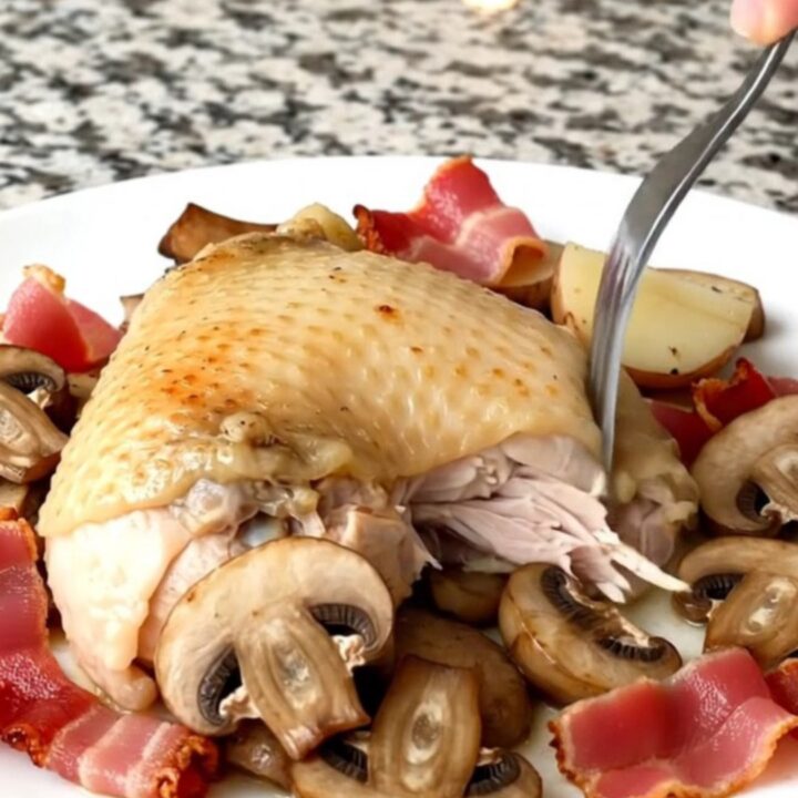 Slow cooker chicken thighs with bacon, mushrooms, and potatoes in a black stoneware insert.