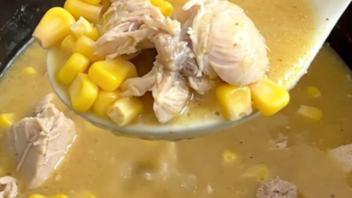 A close-up of a bowl of creamy chicken and sweet corn soup with visible chicken chunks and corn kernels.