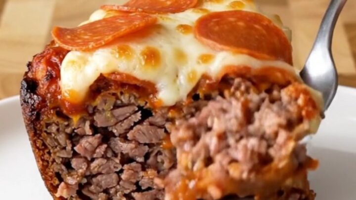A top-down view of a raw meatloaf inside a black slow cooker insert, ready to be cooked with pizza toppings.