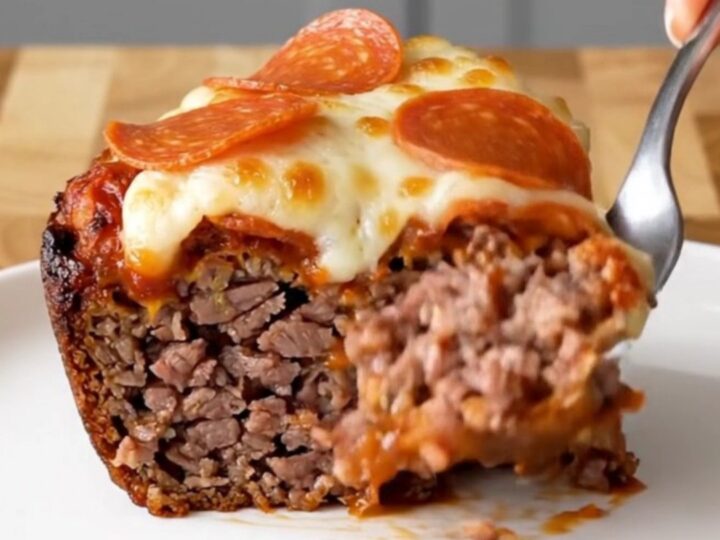 A top-down view of a raw meatloaf inside a black slow cooker insert, ready to be cooked with pizza toppings.