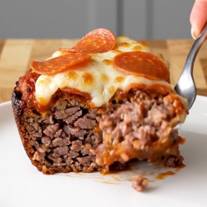 A top-down view of a raw meatloaf inside a black slow cooker insert, ready to be cooked with pizza toppings.