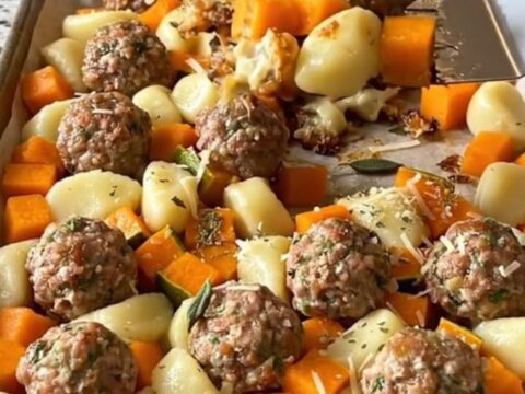 A sheet pan filled with golden roasted gnocchi, turkey meatballs, and butternut squash cubes.