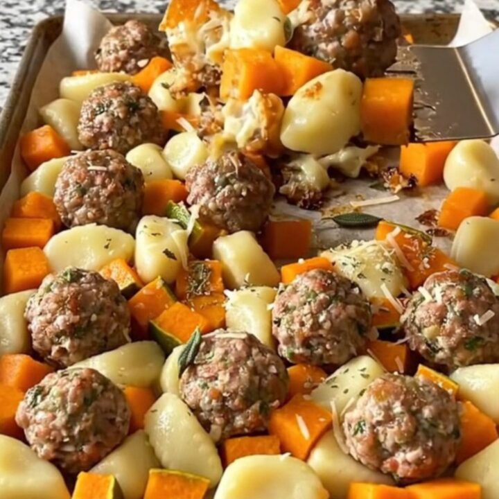 A sheet pan filled with golden roasted gnocchi, turkey meatballs, and butternut squash cubes.