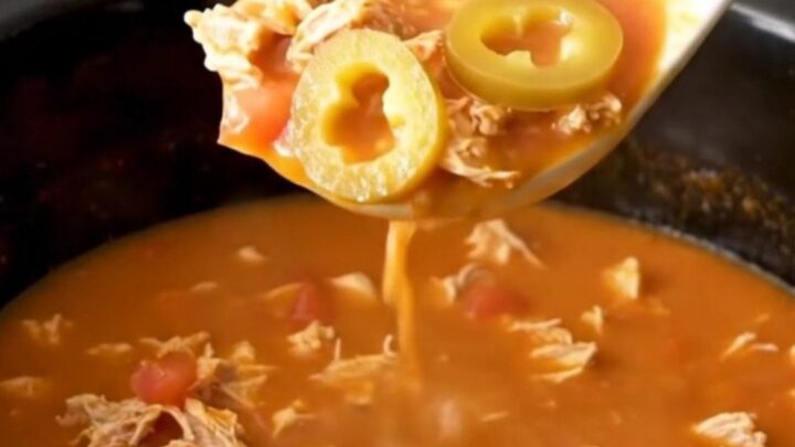 A close-up of creamy tomato-based grinder soup with ground turkey and pepperoncini in a slow cooker.