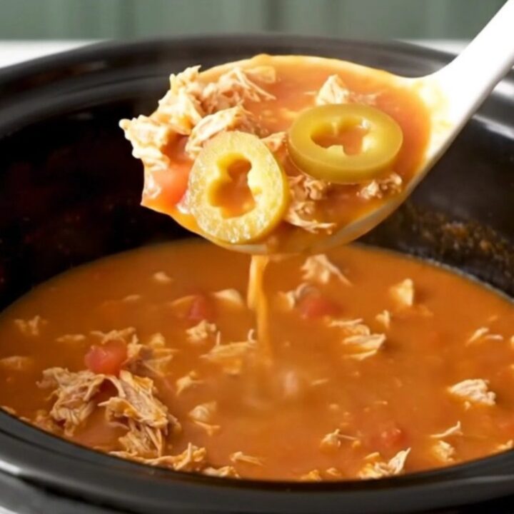 A close-up of creamy tomato-based grinder soup with ground turkey and pepperoncini in a slow cooker.