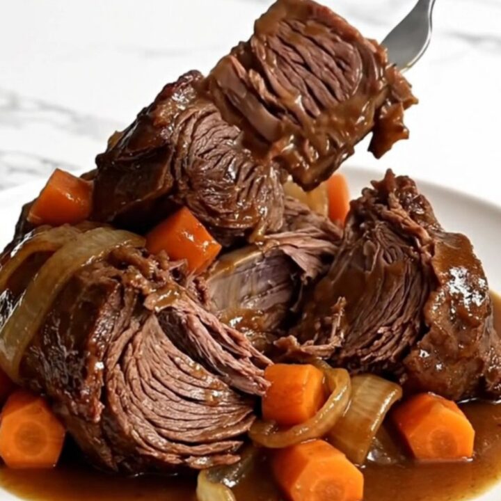 A whole raw beef chuck roast in a slow cooker with carrots and onions.