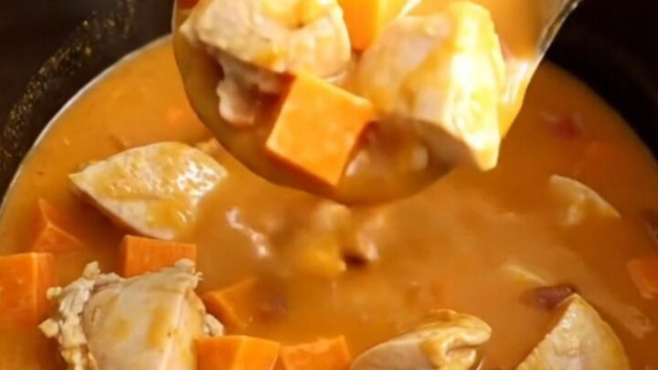 A bowl of smoky chicken, bacon, and sweet potato soup with visible chunks of tender chicken and bright orange potatoes.
