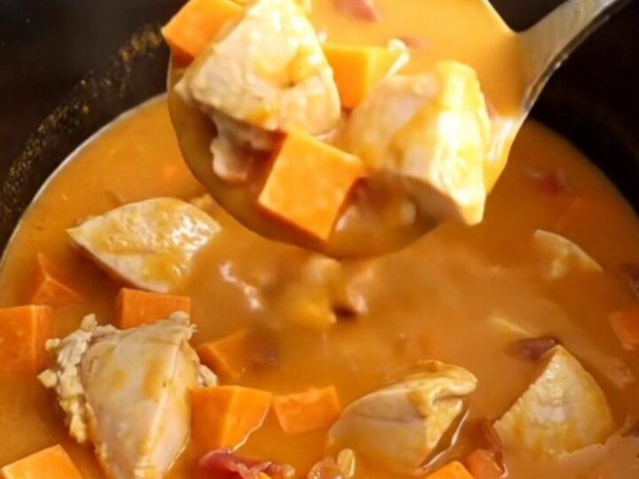 A bowl of smoky chicken, bacon, and sweet potato soup with visible chunks of tender chicken and bright orange potatoes.