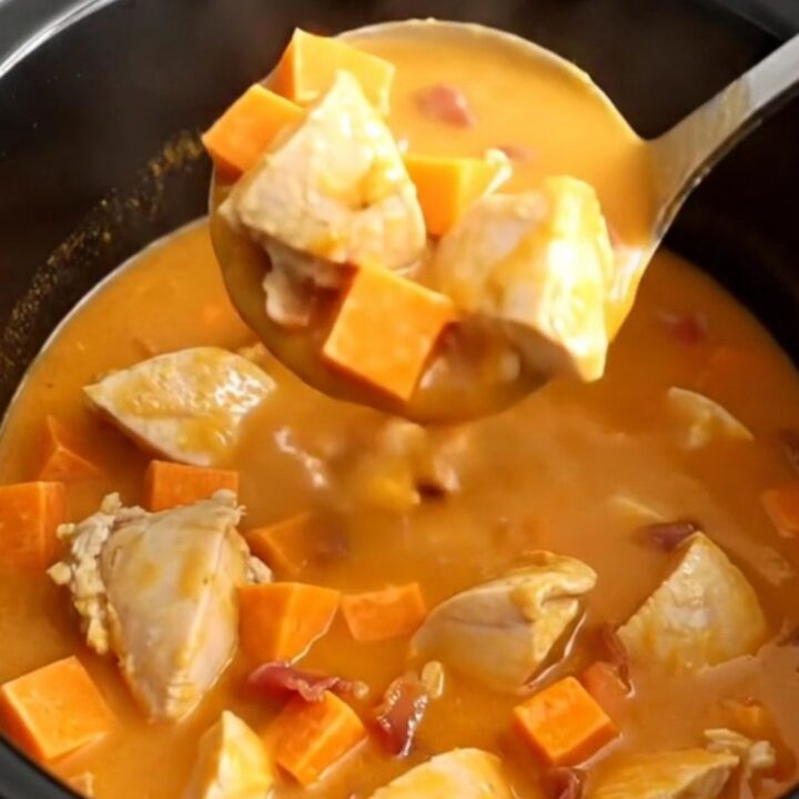 A bowl of smoky chicken, bacon, and sweet potato soup with visible chunks of tender chicken and bright orange potatoes.