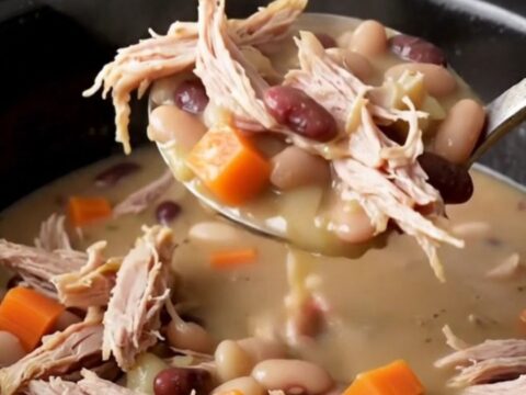 A close-up of a creamy smoked turkey and navy bean stew served in a rustic bowl.