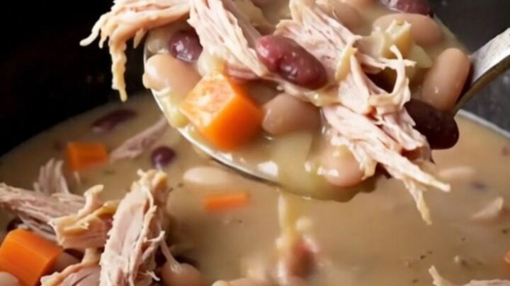 A close-up of a creamy smoked turkey and navy bean stew served in a rustic bowl.