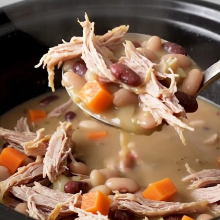 A close-up of a creamy smoked turkey and navy bean stew served in a rustic bowl.