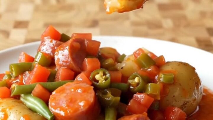 A hearty bowl of slow-cooked kielbasa, baby potatoes, and green beans in a rich, taco-spiced tomato sauce.