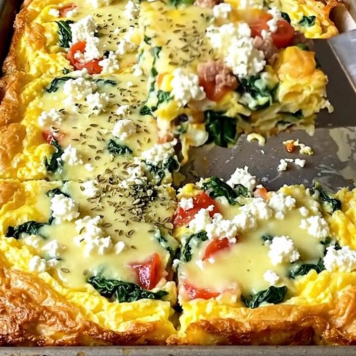A golden-edged egg bake with sausage, spinach, and tomatoes on a sheet pan.