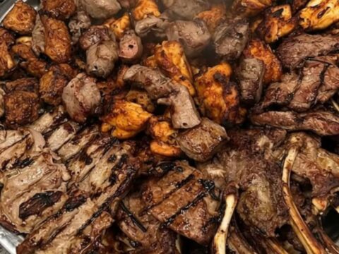 A large silver platter piled high with charred lamb chops, chicken kebabs, and kofta skewers.