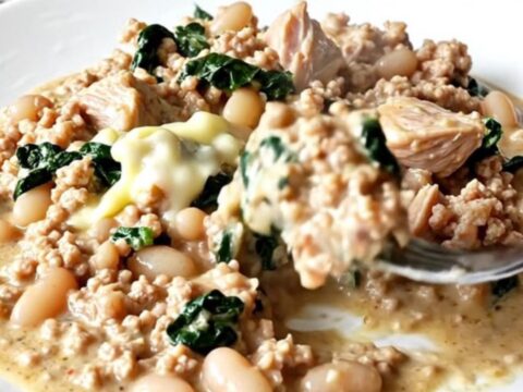 A close-up of creamy Tuscan ground turkey with white beans and spinach in a slow cooker.