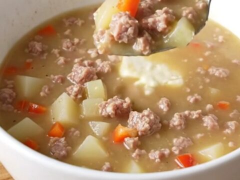 A creamy sausage and potato soup in a slow cooker insert, rich and steaming.