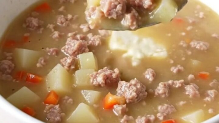 A creamy sausage and potato soup in a slow cooker insert, rich and steaming.