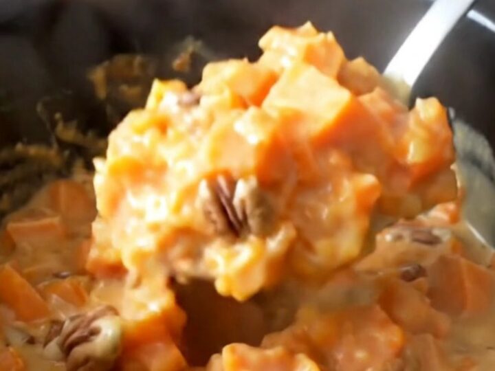 A close-up view of creamy, tender sweet potato chunks in a rich brown sugar and nutmeg glaze with toasted pecans.