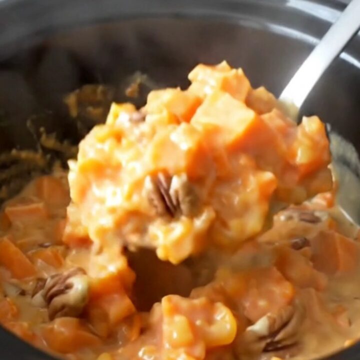 A close-up view of creamy, tender sweet potato chunks in a rich brown sugar and nutmeg glaze with toasted pecans.