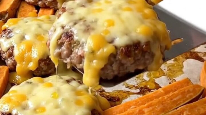 A sheet pan with cooked turkey burgers topped with melted pepper jack cheese and roasted sweet potato wedges.