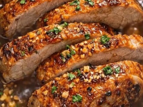Sliced sticky honey garlic pork tenderloin glistening with rich amber glaze inside a slow cooker