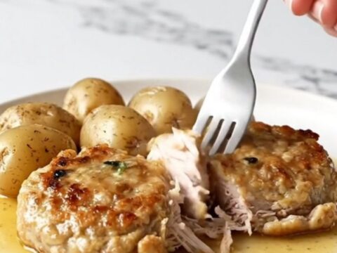 A close-up of golden-tan turkey burger steaks with tender baby potatoes in a savory brown butter sauce.