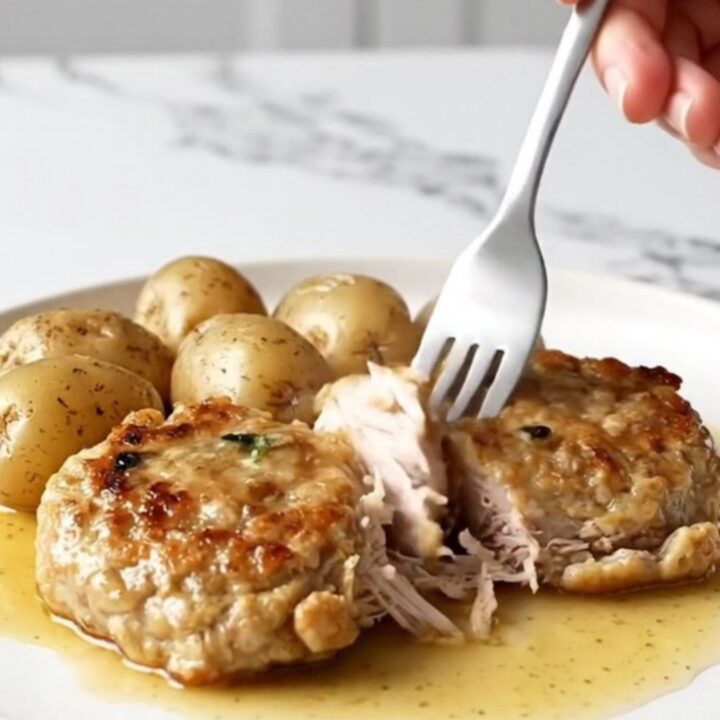 A close-up of golden-tan turkey burger steaks with tender baby potatoes in a savory brown butter sauce.