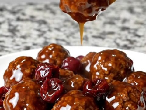A slow cooker filled with beef meatballs coated in a dark cherry bourbon barbecue sauce.