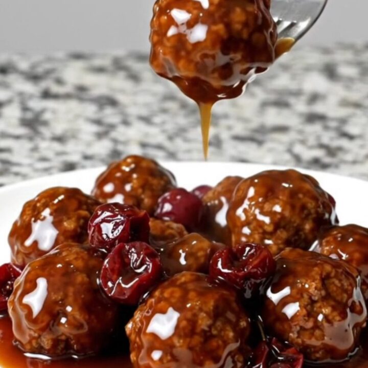 A slow cooker filled with beef meatballs coated in a dark cherry bourbon barbecue sauce.