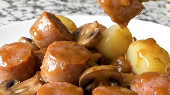 A close-up view of Italian sausage chunks, halved baby potatoes, and mushrooms in a rich Marsala sauce.