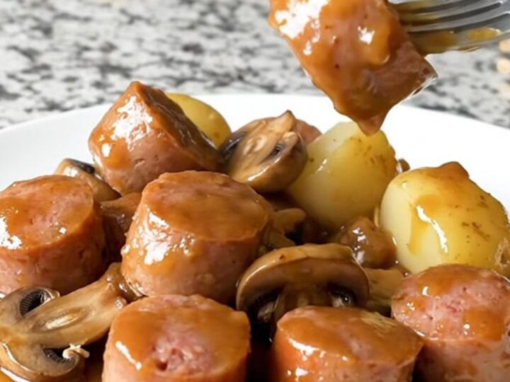 A close-up view of Italian sausage chunks, halved baby potatoes, and mushrooms in a rich Marsala sauce.