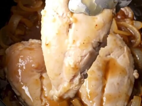 A close-up of tender, golden-tan chicken breasts coated in a thick