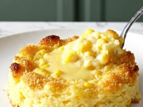 A top-down view of a slow cooker filled with creamy scalloped corn, topped with golden, crispy cracker crumbs.