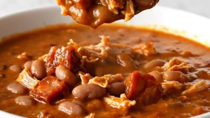 A bowl of rich red turkey and chorizo chili with pinto beans and onions.