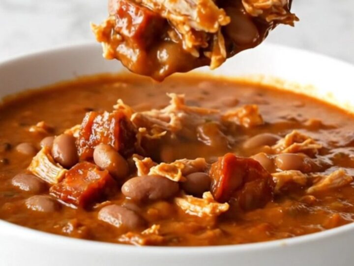 A bowl of rich red turkey and chorizo chili with pinto beans and onions.