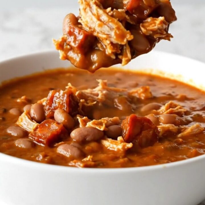 A bowl of rich red turkey and chorizo chili with pinto beans and onions.