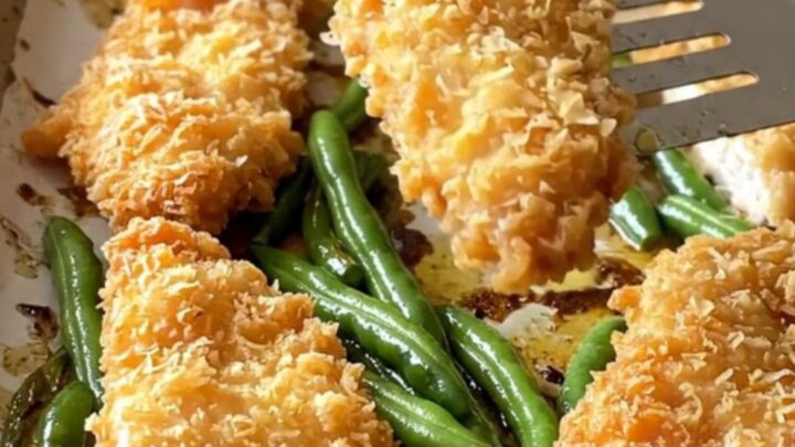 Crispy golden chicken schnitzel tenders and blistered green beans on a parchment-lined sheet pan.