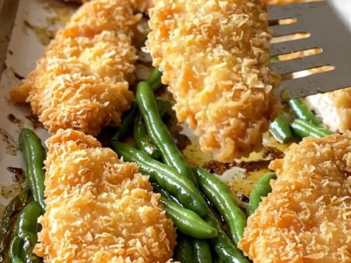 Crispy golden chicken schnitzel tenders and blistered green beans on a parchment-lined sheet pan.