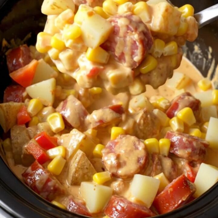 A close-up of the slow cooker filled with creamy andouille sausage, corn, peppers, and tender potato cubes.