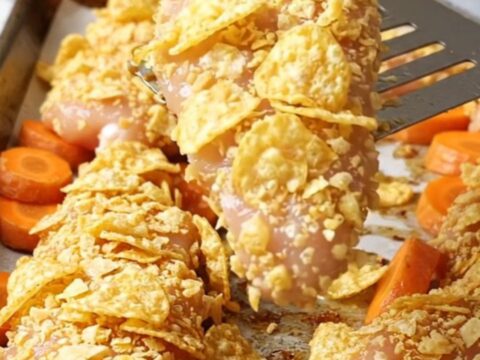 Crispy chicken tenders with a golden potato chip crust and roasted carrot coins on a sheet pan.
