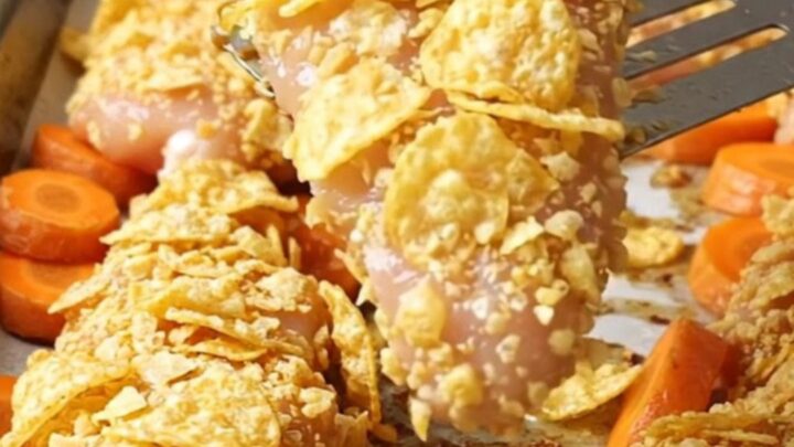 Crispy chicken tenders with a golden potato chip crust and roasted carrot coins on a sheet pan.
